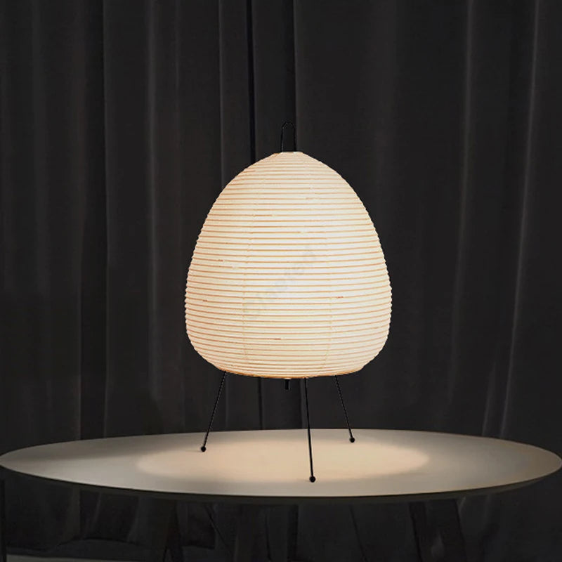 Ribbed rice paper shade glowing against a dark curtain