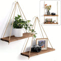 Two swing hanging pine shelves on a wall with a trailing plant and framed photo