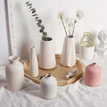 Three matte white ceramic vases on a tray