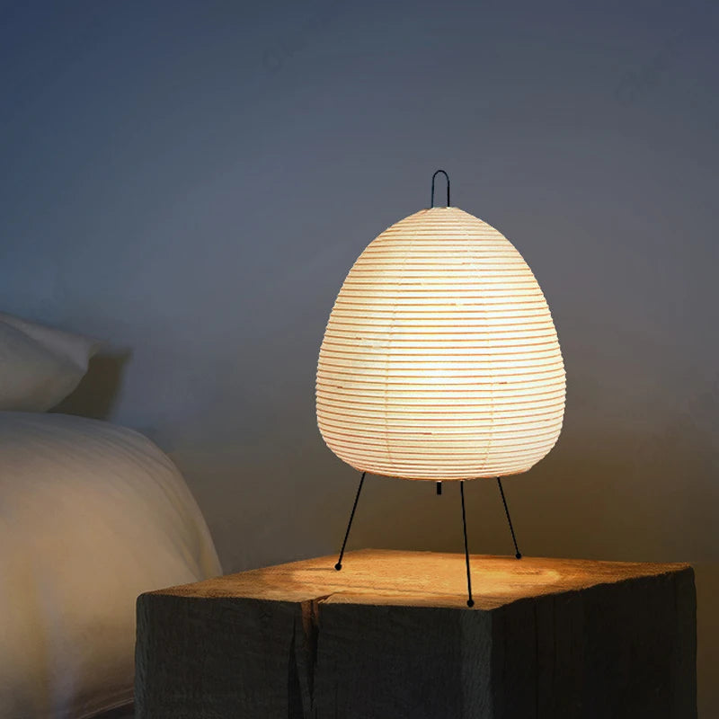 Rice paper lamp lit on a bedside block beside a made bed