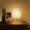 Rice paper table lamp glowing on a walnut sideboard beside dried stems