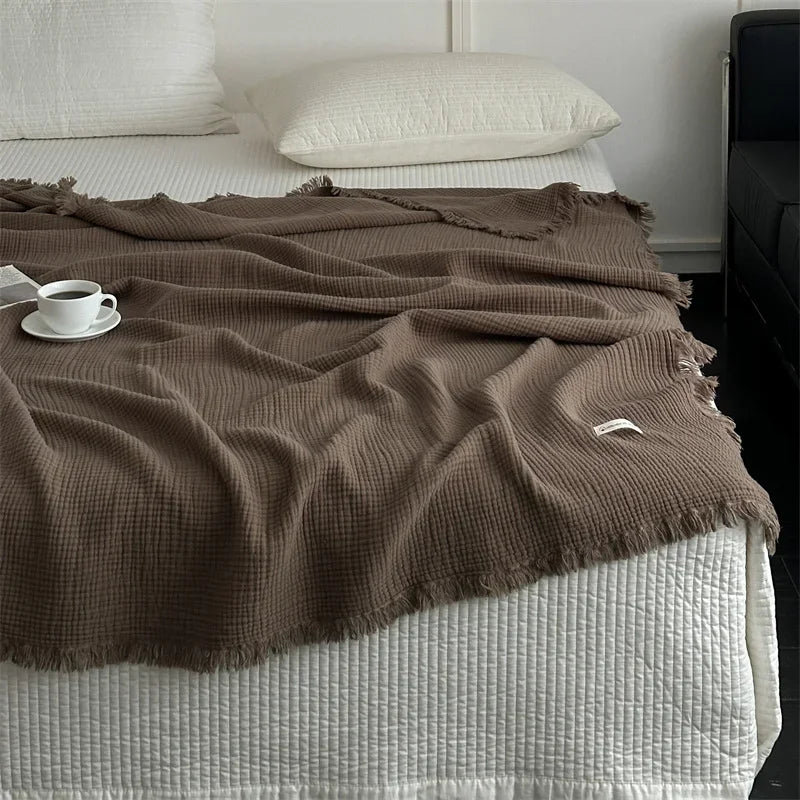 Ember waffle throw folded over a bed with a coffee cup beside it