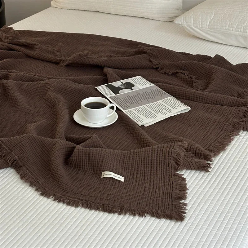 Cotton throw spread on a bed with a newspaper and espresso