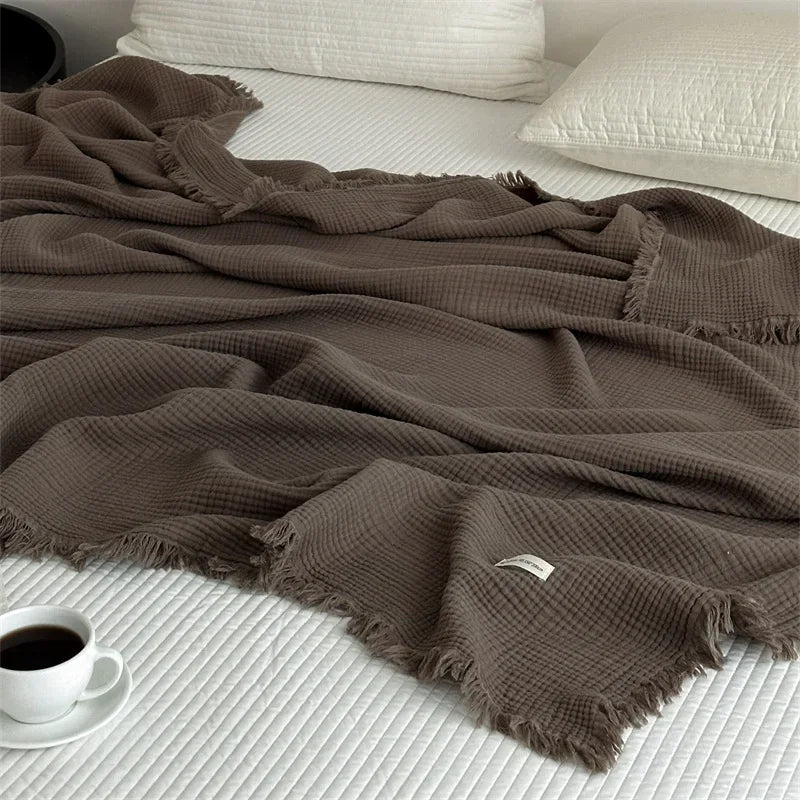 Cocoa brown waffle cotton throw draped across a bed with cream pillows