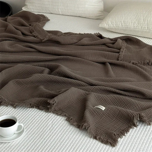 Cocoa brown waffle cotton throw draped across a bed with cream pillows