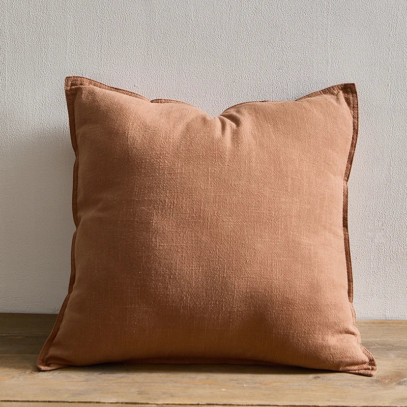 Rust cotton and ramie cushion against a pale wall