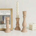 Two turned wood candlesticks beside a framed print